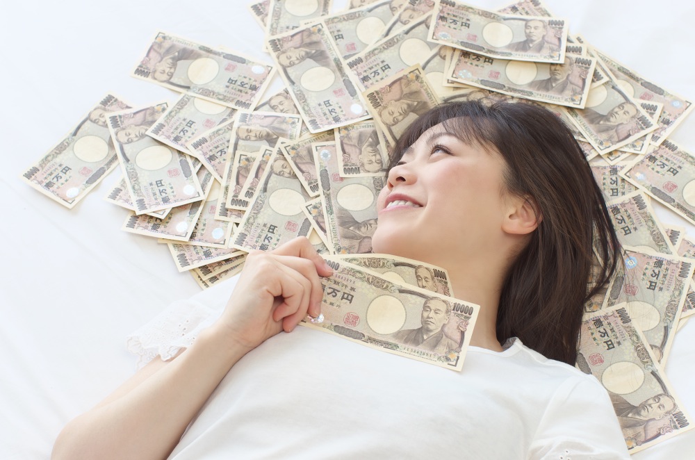 一万円札の上で寝転ぶ女性